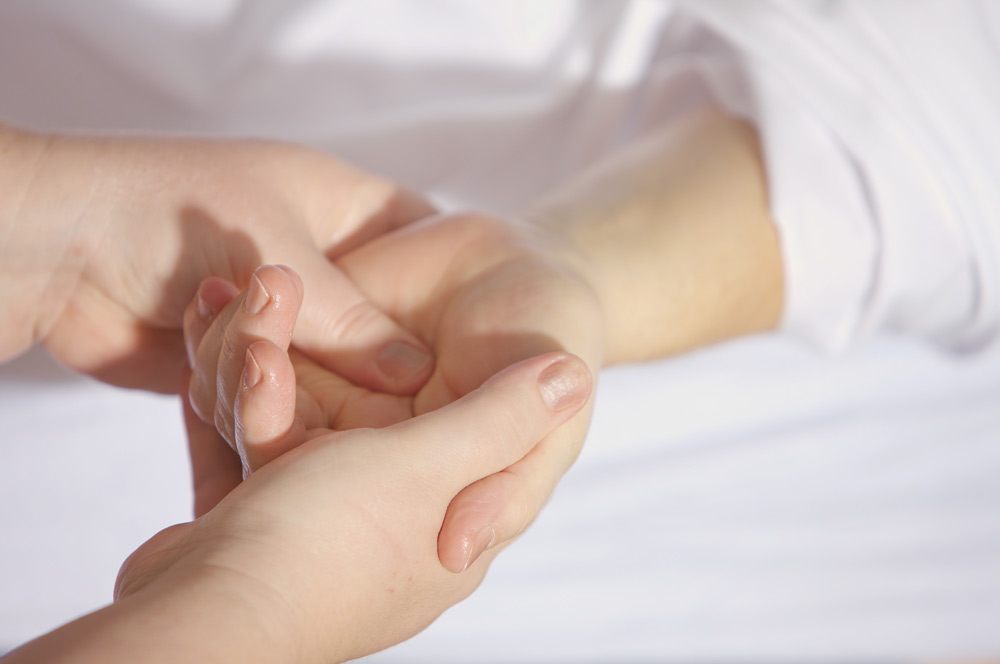 Närbild på en patient som får massage i handflatan